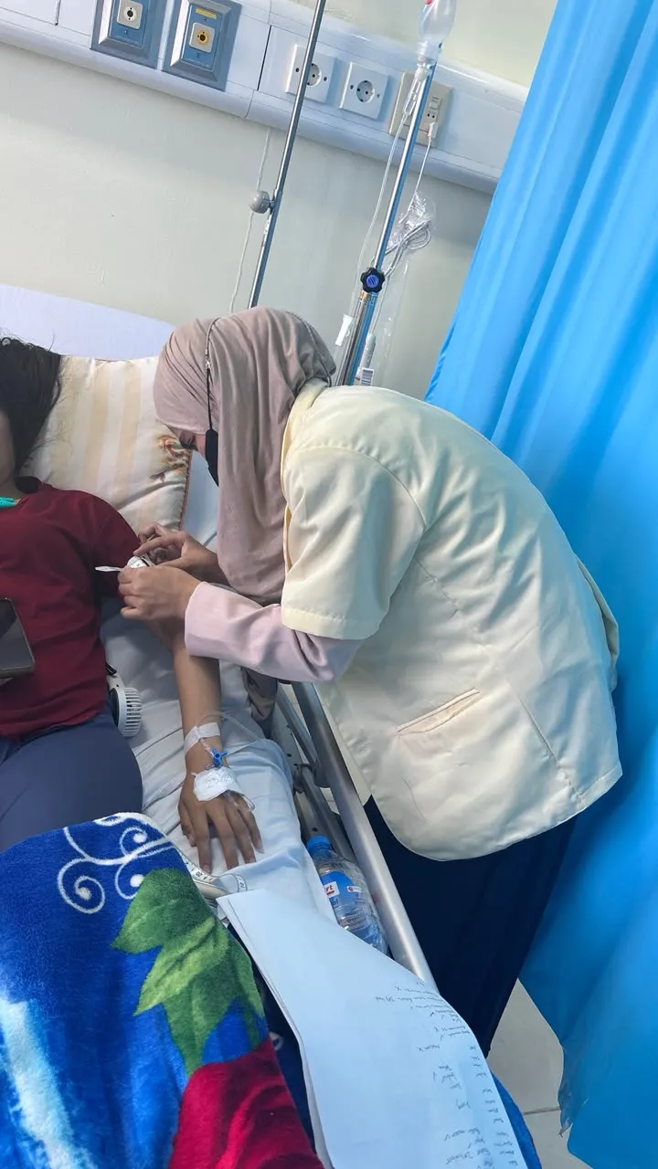 Henni in a nutrition jacket at a hospital bedside during the dietetic internship